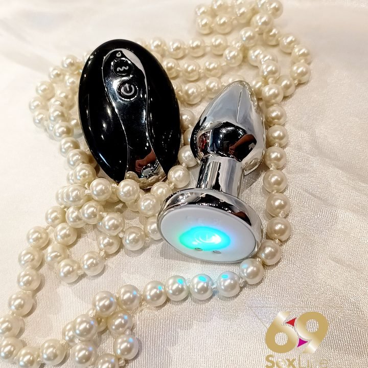 Plug anal de metal com pedra azul sobre colar de pérolas